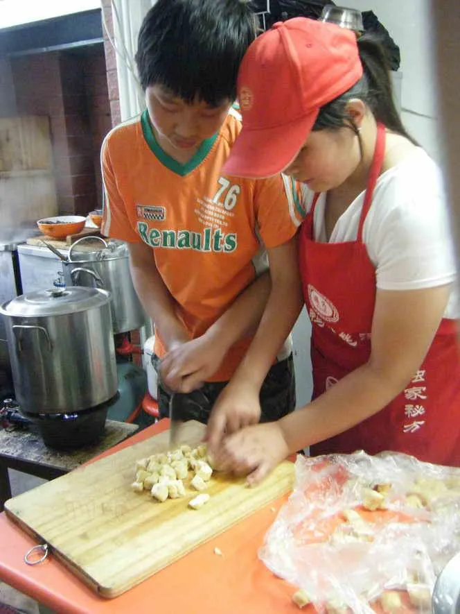 这位同学切油豆腐的样子还真像，学得很仔细呢！